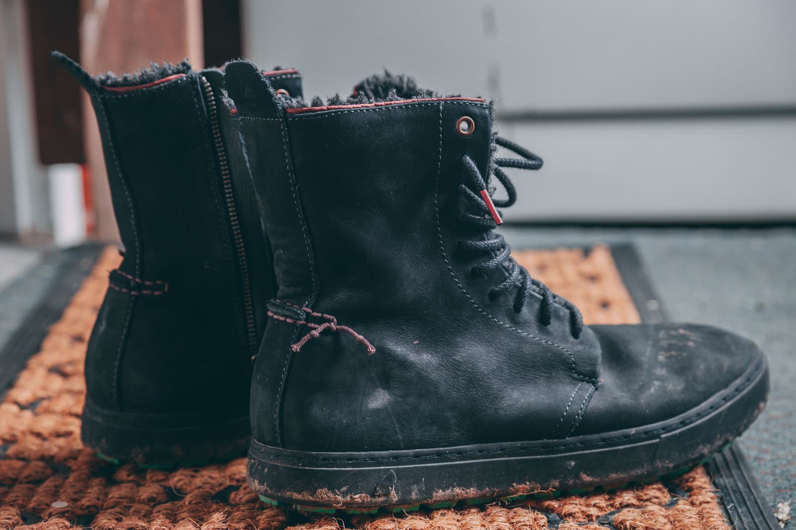 Muddy boots and a wet doormat at the entrance to a home