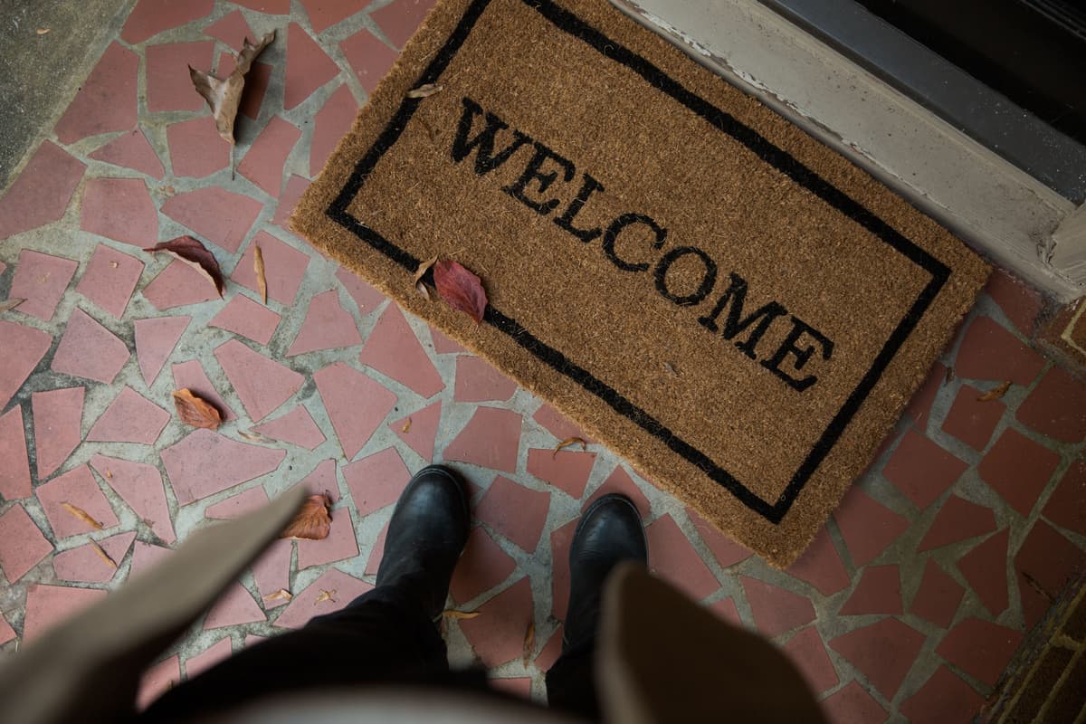 Muddy boots standing on a doormat at a house entrance