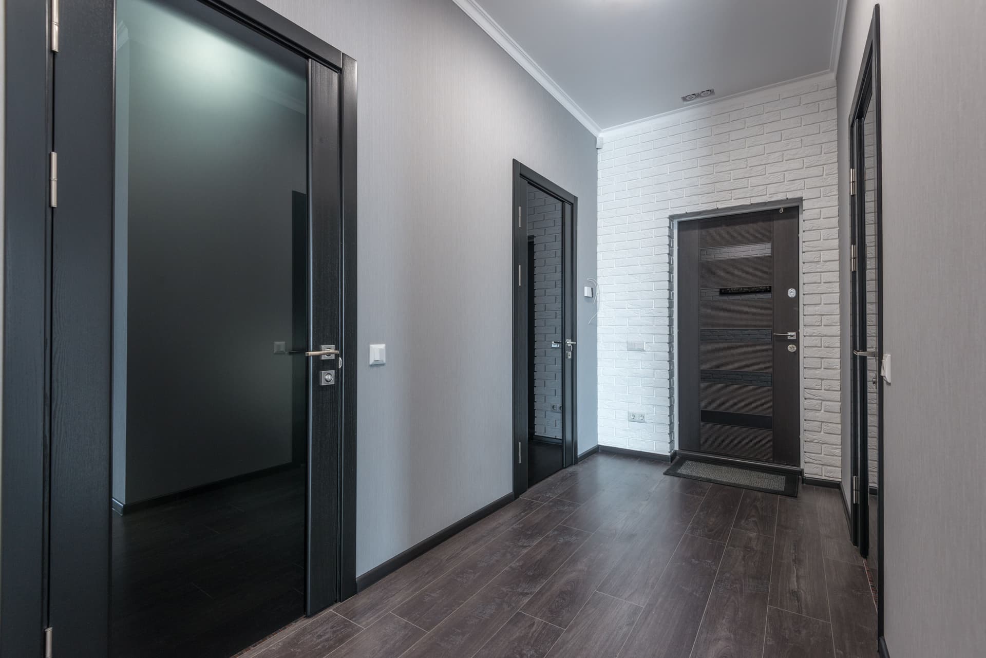 A home entryway hall with a mat, boots and a coat rack